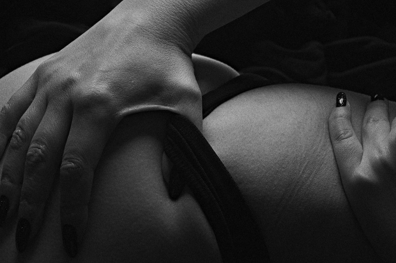 our-story-02 A sensual black and white close-up of hands touching skin, conveying intimacy and connection.