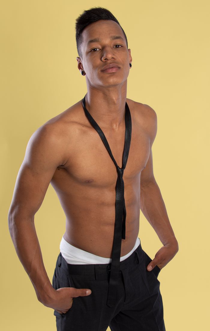 why-choose-us-02 Topless male model posing confidently with a tie against a yellow backdrop.
